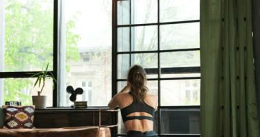 Sıska, genç, beyaz bir kadın sporcunun arka tarafında, evde kendini izole etme modunda egzersiz yapıyor. Spor yapan, spor yapan ve oturma odasında bacakları için çömelen bir kadın..