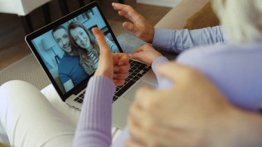 Yaşlı çiftin evde çocuklarla görüntülü konuşma yapmak için dizüstü bilgisayar kullanırken yakın plan çekimleri..