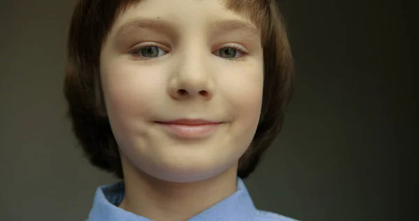 Närbild porträtt av söt liten pojke i blå skjorta tittar mot kameran och ler. — Stockfoto