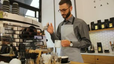 Modern kahve dükkanındaki müşterilere kahve hazırlayan bardaklı çekici baristanın portresi. Yandan görüntüle.