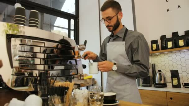 Barista guapo en las copas preparando taza de café para el cliente en la cafetería moderna. Vista desde el costado . — Vídeo de stock