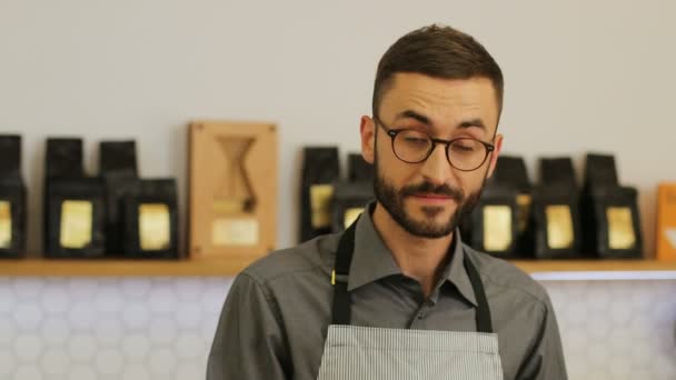 Primer plano retrato de feliz macho hipster barista en la cafetería possing y sonriendo en cámara . — Vídeo de stock