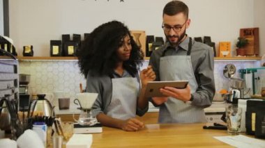 Genç iş adamının portresi, iş günü Afrikalı kadın çalışana tablette yeni bir kafe menüsü gösteriyor..