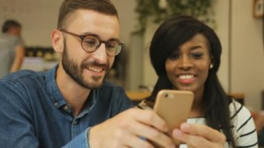 Genç ve çekici hipster 'ın şık bir kafede kahve içerken yakın plan fotoğrafı. Kadın ekrana bakarken adam akıllı telefon kullanıyor..