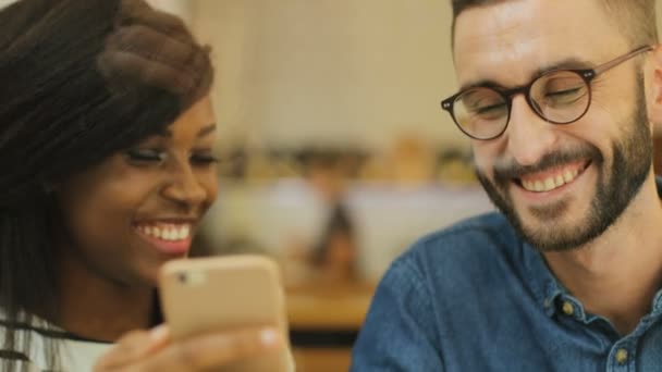 Närbild bild bild av unga attraktiva hipster dricka kaffe med sin kvinnliga vän i urban café, man med hjälp av smart telefon medan kvinna tittar på skärmen. — Stockvideo