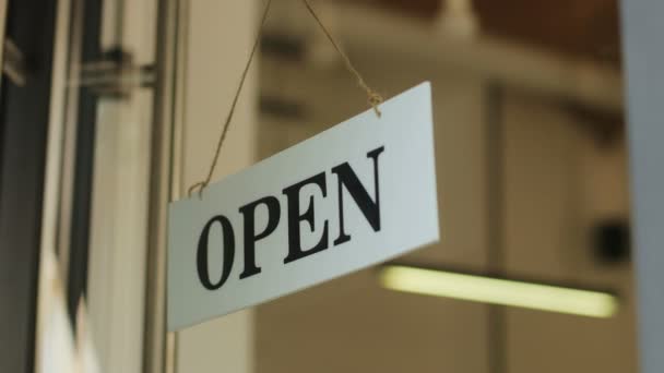 Primer plano del atractivo hombre hipster girando un cartel "abierto" en la ventana de su cafetería. El dueño joven de la cafetería que cierra la cafetería . — Vídeos de Stock