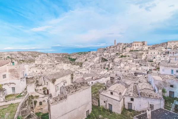 Typický dům z kamenů (Sassi di Matera) a kostel Matera pod modrou oblohou. Matera, Itálie — Stock fotografie