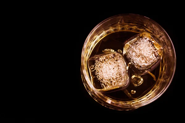Ansicht von Whisky im Glas mit Eiswürfeln auf schwarzem Hintergrund, Fokus auf Eiswürfel — Stockfoto
