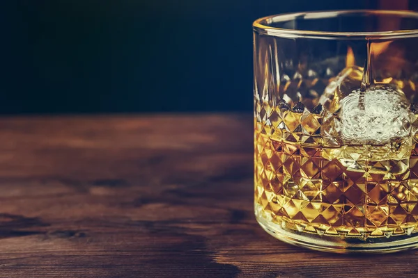Bicchiere di whisky con cubetti di ghiaccio sul tavolo di legno, atmosfera calda — Foto Stock