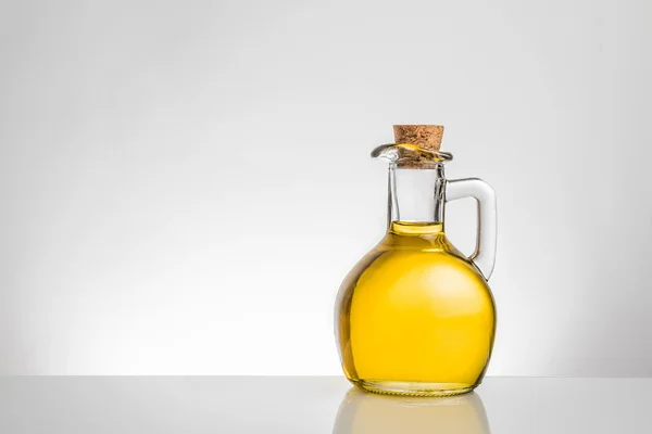Контейнер с оливковым маслом с пробкой на сером фоне — стоковое фото