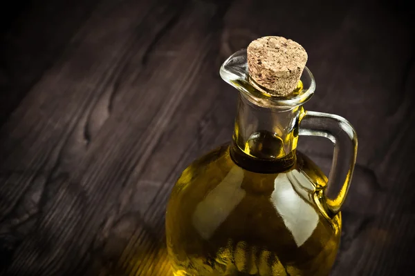 Контейнер из-под оливкового масла с пробкой на фоне деревянного стола — стоковое фото