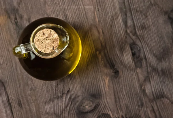 Vue du dessus de la bouteille de récipient d'huile d'olive avec bouchon sur fond de table en bois — Photo