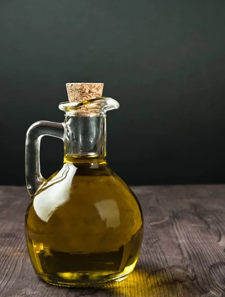 Olijfolie container fles met kurk op houten tafel achtergrond — Stockfoto