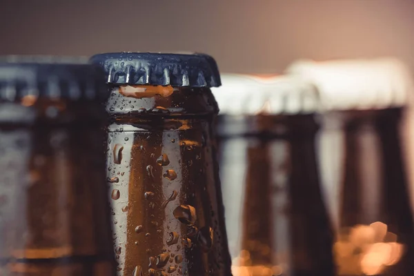 Close-up of fresh cold beer ale bottles with drops and focus on stopper — Stock Photo, Image