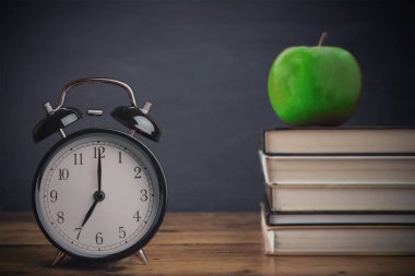 vintage eski çalar saat yakınındaki blackboard ve elma meyve karşı yığılmış kitaplar okul hazırlıkları 