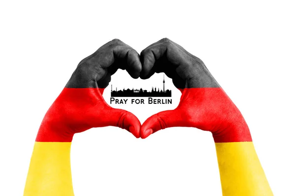 Prega per berlin, germania, silhouette della città dentro le mani dell'uomo sotto forma di cuore con la bandiera della Germania sullo sfondo bianco, concetto per le vittime di berlin — Foto Stock