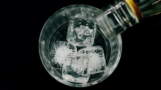 Barman pouring whiskey with ice cubes in the glass on wood table, view top — Stock Video