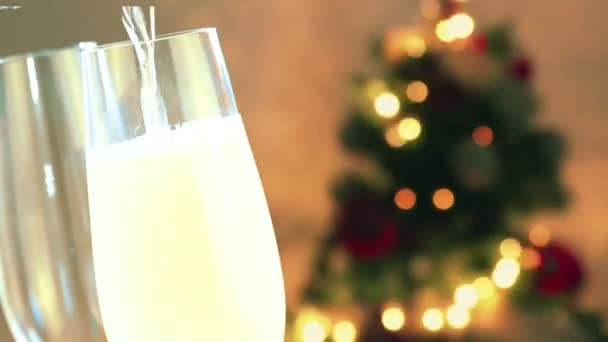 Pouring champagne into flutes with golden bubbles with golden abstract blinking blurred Christmas tree lights bokeh on gold warm background, christmas festive holiday — Stock Video