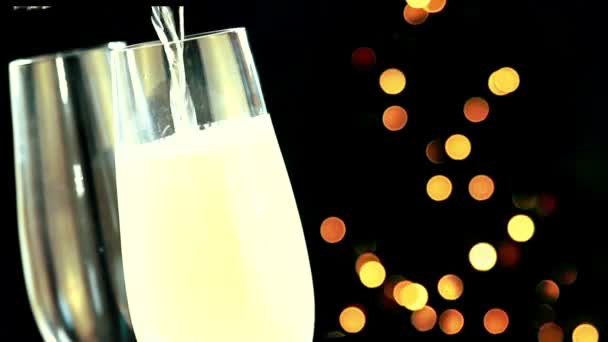 Versando champagne in flauti con bolle d'oro con oro astratto lampeggiante sfocato albero di Natale luci bokeh su sfondo nero, Natale festa — Video Stock