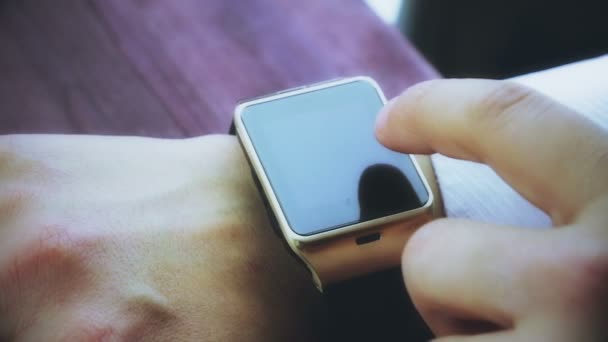 Ο άνθρωπος χρησιμοποιώντας εφαρμογή smartwatch με το δάχτυλό του στο ξύλινο τραπέζι, νέα τεχνολογία — Αρχείο Βίντεο