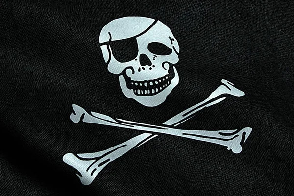 Tessitura in tessuto della bandiera pirata sventolando nel vento, simbolo pirata jack calico, hacker e ladro — Foto Stock