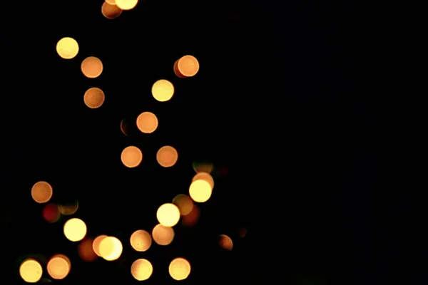 Goldene abstrakte blinkende verschwommene Weihnachtsbaumbeleuchtung Bokeh auf schwarzem Hintergrund, festlicher Feiertag — Stockfoto