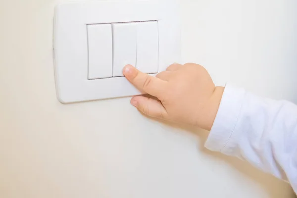 Adorável menino criança ligando o interruptor de luz branca — Fotografia de Stock