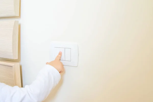 Adorável menino criança ligando o interruptor de luz branca — Fotografia de Stock