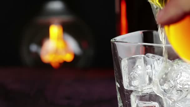 Barman versant du whisky avec des glaçons sur une table en bois, ambiance chaleureuse, moment de détente avec du whisky avec une ampoule vintage chaude et légère — Video