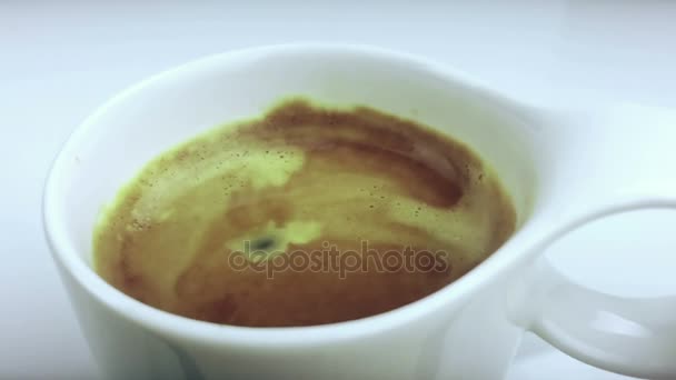 Goutte de café tombant au ralenti à l'intérieur de la tasse de café italien expresso avec mousse sur fond blanc, nourriture et boisson et se détendre — Video