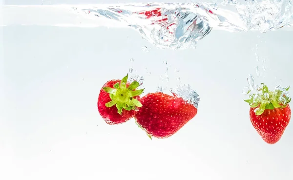 Červené ovoce jahody spadající do vody s úvodní na bílém pozadí, jahod pro zdraví a diety, výživa — Stock fotografie