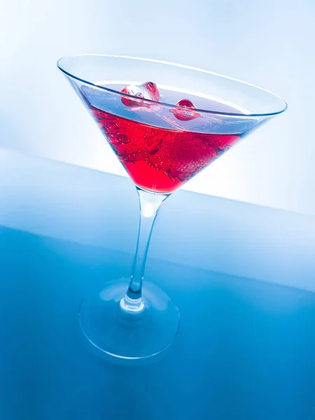 Rode cocktail drinken met ijsblokjes op blauwe lichte tint achtergrond, plezier en dans disco — Stockfoto