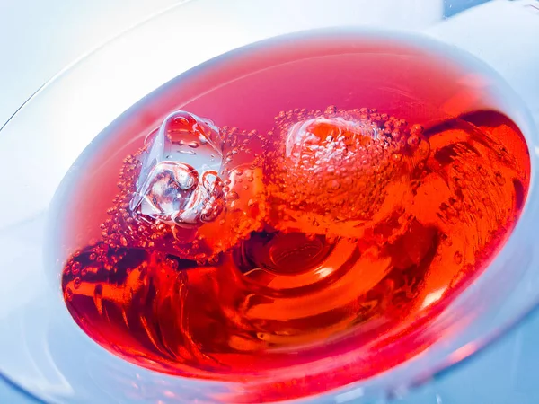 Close-up de bebida de coquetel vermelho com cubos de gelo em fundo de tonalidade de luz azul, diversão e dança disco — Fotografia de Stock