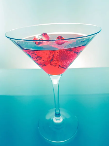 red cocktail drink with ice cubes on green light tint background, fun and dance disco