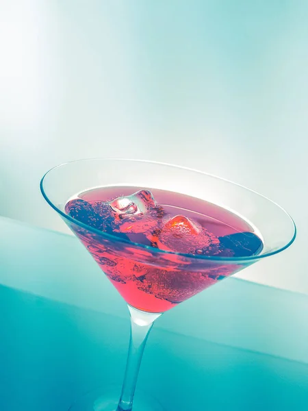 Bebida coquetel vermelho com cubos de gelo no fundo de tonalidade de luz verde, diversão e discoteca de dança — Fotografia de Stock