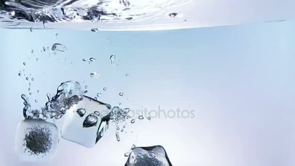 Cubos de hielo cayendo salpicaduras en el agua sobre fondo blanco, tiro en cámara lenta, bebida fresca hora de verano — Vídeo de stock