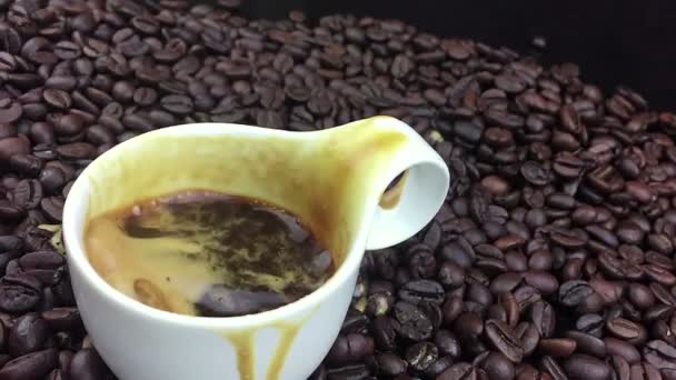 Goutte de café tombant au ralenti à l'intérieur de la tasse de café italien expresso avec mousse sur fond de grains de café, nourriture et boisson et se détendre — Video