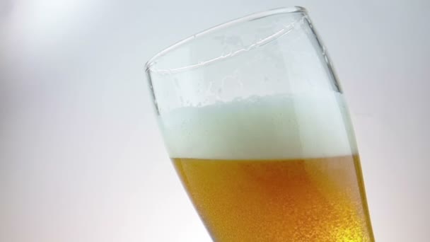 Färsk öl med skum i drink pint glas med is fryst droppar, sköt slowmotion på vit bakgrund, kul och näringslära mat och dryck — Stockvideo