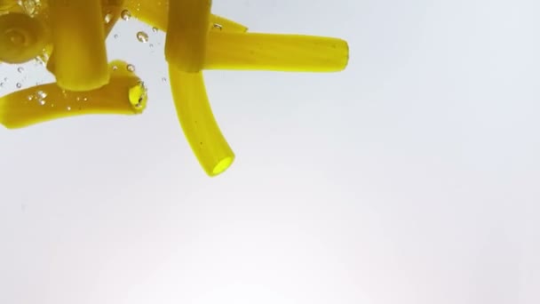 Сплеск макаронних макаронних виробів падає у кип'ячену воду, знімається повільно на білому тлі, італійське харчування та охорона здоров'я — стокове відео