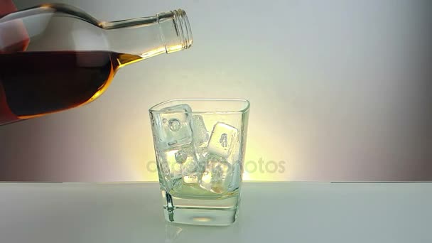 Barman whiskey met fles in het drinken glas met ijsklontjes gieten op warme witte achtergrond, tijd voor een ontspannen drankje met whisky — Stockvideo