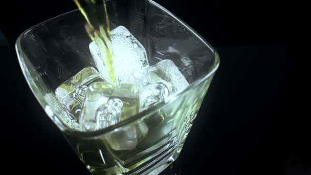 Arriba de la vista del barman vertiendo whisky en el vaso con hielo sobre fondo negro, tiempo de relax con whisky — Vídeo de stock
