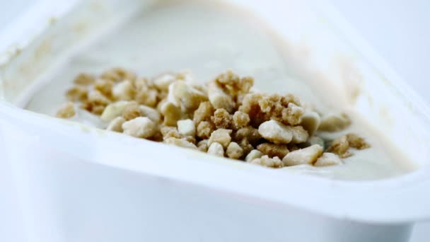 Close-up of healthy cereal and chocolate on white yogurt and spoon, shot in slow motion , concept of healthy food — Stock Video