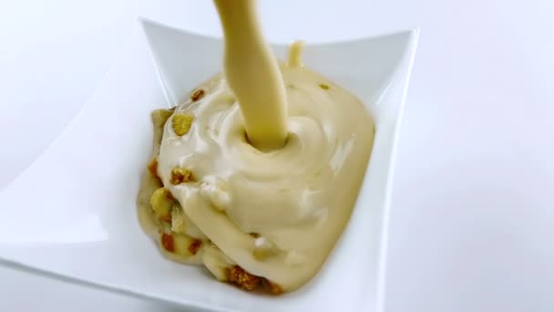 Йогуртовый крем с хлопьями и шоколадом, наливание и брызги в замедленной съемке на белое стекло контейнера, концепция здорового питания — стоковое видео