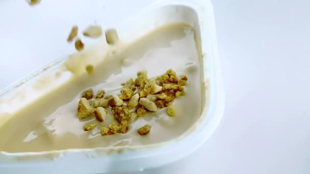 Γκρο πλαν, υγιεινά δημητριακά και σοκολάτα που πέφτουν σε αργή κίνηση σε λευκό γιαούρτι με το κουτάλι, η έννοια της υγιεινής διατροφής — Αρχείο Βίντεο