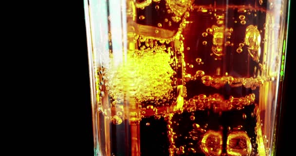 Close-up of drinking glass of spritz aperitif aperol orange cocktail with ice cubes, with fizzy bubbles movement on black background, holiday and summer time — Stock Video