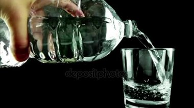 içme cam şişe siyah arka plan üzerine aracılığıyla kabarcıkları ile su ile doldurma, ağır çekim, beslenme ve sağlık sağlık vurdu 