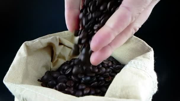 Man hands holding coffee beans in canvas sack and some falling down, shot slow motion on dark background, agriculture and nutrition — Stock Video