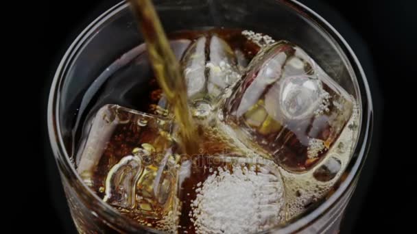 Arriba de la vista verter de coque fresco en el vaso de la bebida con los cubos de hielo en el fondo negro, diversión y hora de verano — Vídeo de stock