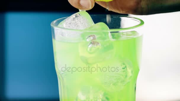 Muž squeeze žlutá citron na pití alkoholu koktejl do sklenice s kostkami ledu, noční klub světlo — Stock video