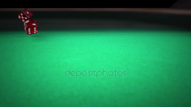 Tres dados rojos rodando en la mesa de juego verde sobre fondo negro, tiro con cámara lenta, concepto de deporte recreación juego de ocio — Vídeos de Stock
